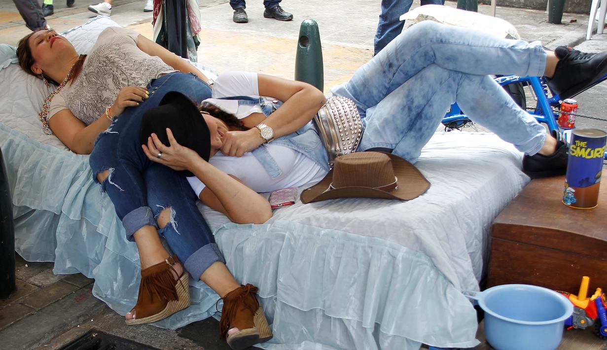 Dua wanita berbaring di tempat tidur saat merayakan Hari Malas Sedunia di Ibague, Kolombia, (14/8). Sejumlah orang turun ke jalan membawa tempat tidur dan maainanya untuk bermalas-malasan. (REUTERS/Fredy Builes)
