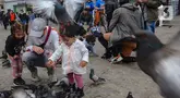 Wisatawan berkumpul sambil memberi makan dan bermain dengan burung merpati di Dam Square, Amsterdam, Belanda, Sabtu (26/5/2024). (merdeka.com/Arie Basuki)