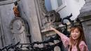Wisatawan berfoto dekat patung 'Manneken Pis' dalam balutan baju bermotif bunga di ibu kota Belgia, Brussels, Senin (12/8/2019). Patung anak laki-laki yang sedang buang air kecil ini menjadi salah satu daya tarik uta di kota cantik tersebut. (Photo by Kenzo TRIBOUILLARD / AFP)
