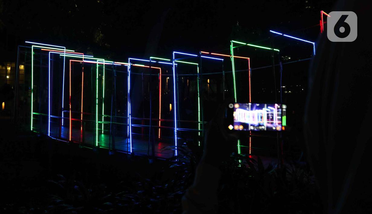 Warga saat memotret Jakarta Lights Festival di Taman Sumenep, Jakarta, Jumat (23/12/2022). Pemprov DKI Jakarta menggelar acara Jakarta Lights Festival sebagai rangkaian perayaan Natal dan Tahun Baru (Nataru) 2023. (Liputan6.com/Herman Zakharia)