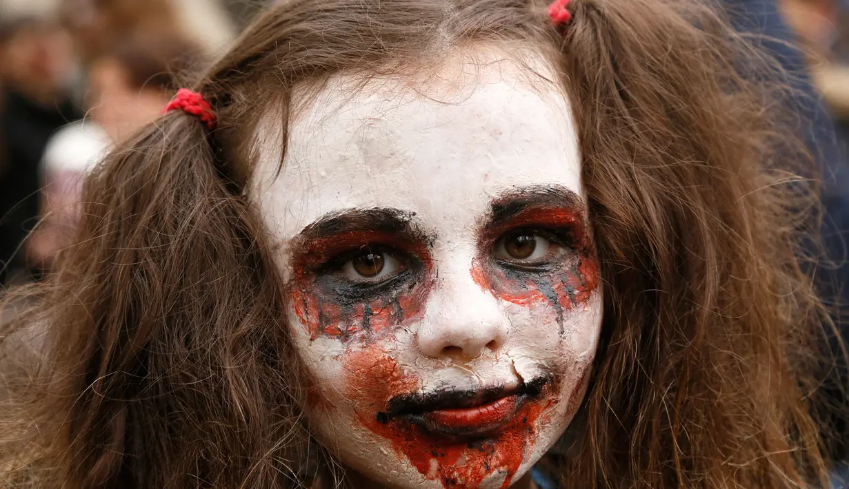 Seorang anak berpose dengan dandanan menyerupai zombie ketika berpartisipasi dalam 'Zombie Walk' di pusat Kota Kiev, Ukraina, 26 Oktober 2019. Menjelang perayaan Halloween pada 31 Oktober mendatang, warga di beberapa belahan dunia sudah mulai melakukan acara bertema horor. (AP/Efrem Lukatsky)