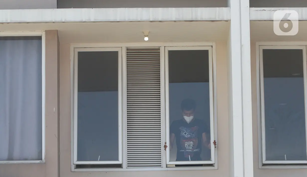 Seorang pasien COVID-19 terlihat membuka jendela di rumah isolasi terpusat Bekasi Berantas Pendemi (Berani) di Jababeka, Cikarang, Kabupaten Bekasi, Rabu (28/7/2021). Rumah isolasi tersebut dapat menampung 660 pasien COVID-19 bergejala ringan dan tenaga kesehatan. (Liputan6.com/Herman Zakharia)