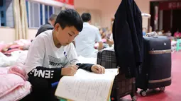 Seorang anak laki-laki mengerjakan tugas sekolahnya di tempat penampungan sementara di Bikou di Wilayah Wenxian, yang terletak di Kota Longnan, Provinsi Gansu, China barat laut (18/8/2020). (Xinhua/Chen Bin)