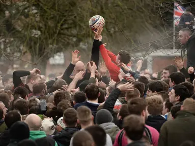 Sejumlah pria berebut bola saat perayaan The Royal Shrovetide Football Match, Inggris, Selasa (28/2). Tradisi ini adalah sebuah pesta rakyat menyambut datangnya Hari Raya Paskah. (AFP Photo/ Oli SCARFF)