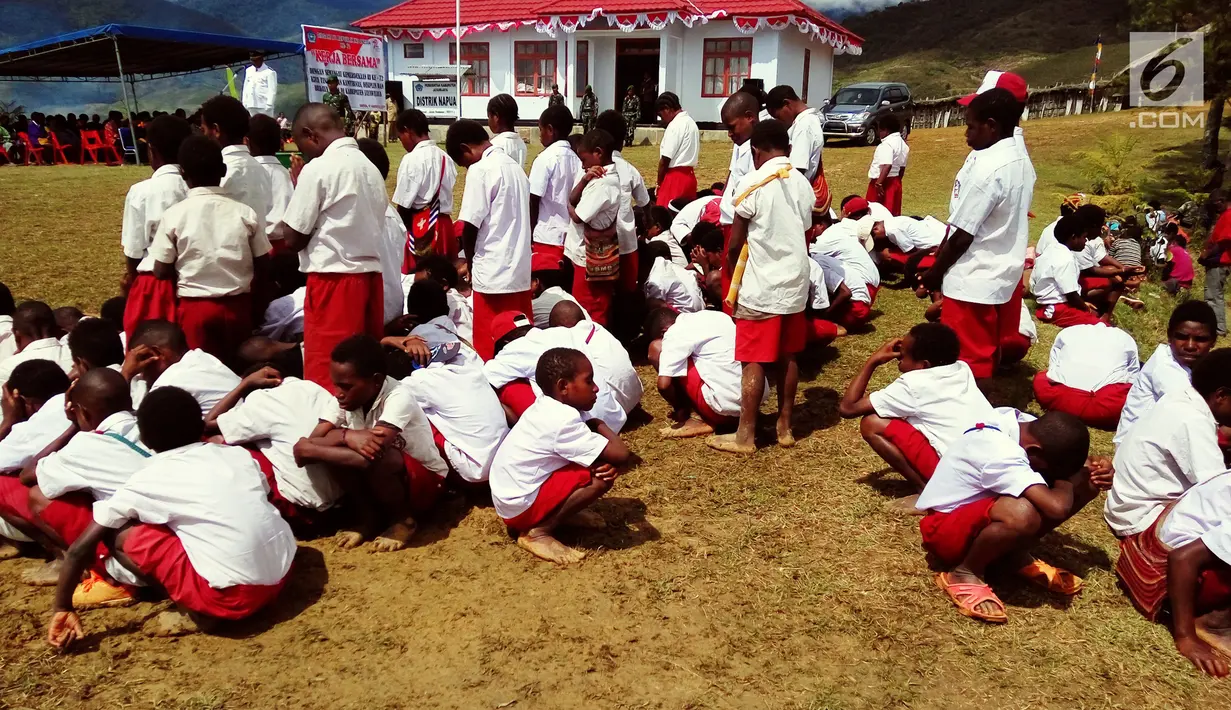 Murid Sekolah Dasar (SD) mengheningkan cipta saat upacara pengibaran bendera di Kantor Pemerintah Kabupaten Jayawijaya, Provinsi Papua, Kamis (17/8). Terlihat sebagian murid  berjongkok karena kelelahan dan mengantuk. (Foto: Fitri Haryanti Harsono)