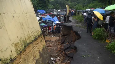 Petugas penyelamat dan warga berkumpul di lokasi runtuhnya tembok di Mumbai, India (2/7/2019). Sedikitnya 15 orang tewas dan 69 orang lainya luka ketika sebuah tembok runtuh saat hujan lebat monsun. (AFP Photo/Punit Paranjpe)