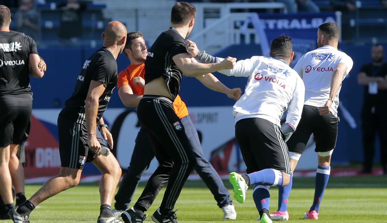 Seorang suporter masuk ke lapangan dan menyerang pemain Lyon yang sedang melakukan pemanasan di Armand Cesari stadium, Bastia, (16/4/2017). Laga ini akhirnya dihentikan LFP. (AFP/Pascal Pochard-Casabianca)