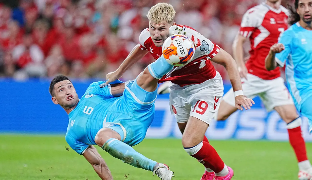 Bek Timnas San Marino, Dante Rossi (kiri) berebut bola dengan striker Timnas Denmark, Jonas Wind pada laga matchday kelima Grup H Kualifikasi Euro 2024 di Copenhagen, Denmark, Jumat (8/9/2023) dini hari WIB. (AFP/Ritzau Scanpix/Liselotte Sabroe)