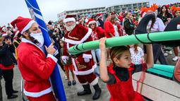 Sejumlah pengunjung berkostum Sinterklas bersiap melakukan selancar dalam acara Surfing Santa yang berlangsung di Pantai Cocoa, Florida, Amerika Serikat, Selasa (24/12/2024) waktu setempat. (AFP/Giorgio Viera)