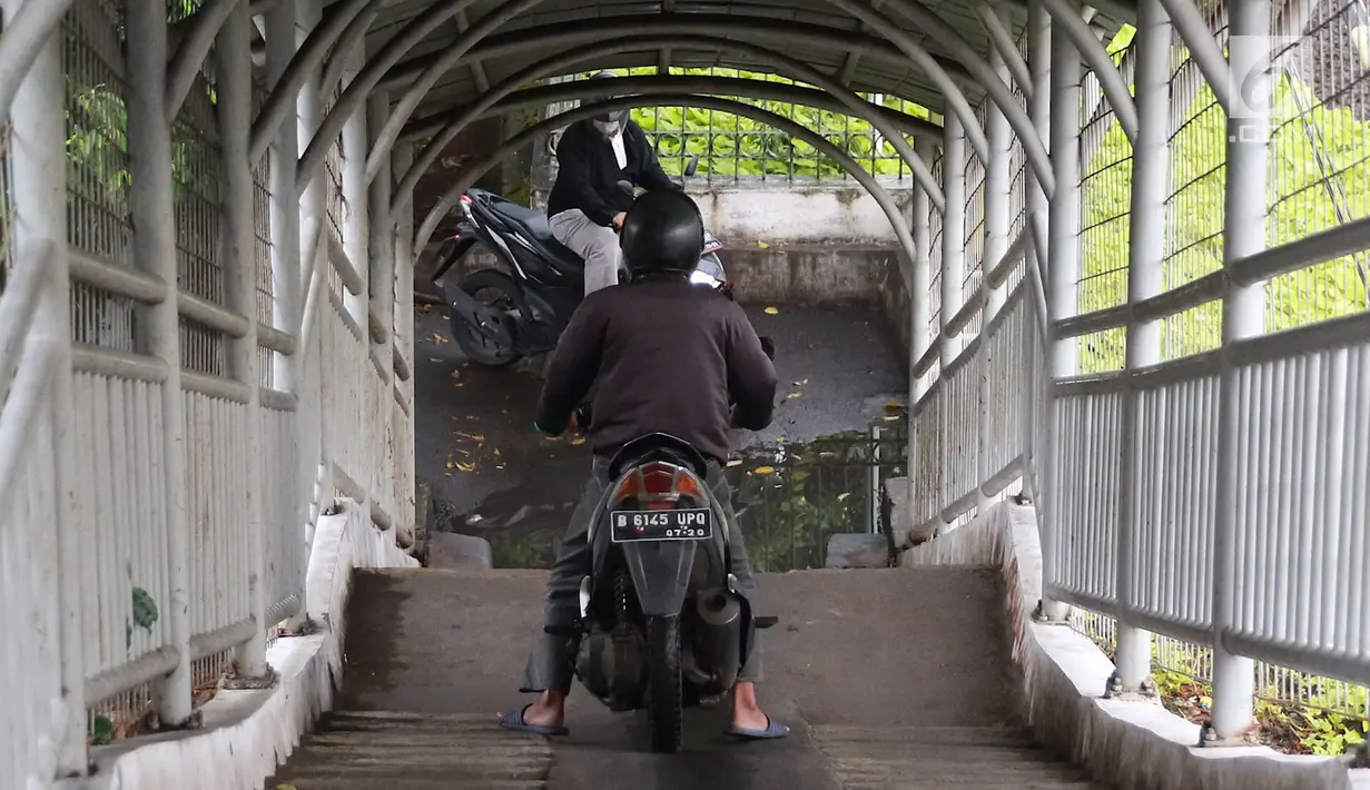 Pemotor melintasi jembatan penyeberangan orang (JPO) di kawasan Pasar Minggu, Jakarta, Rabu (24/4). Kurangnya kesadaran akan tertib berlalu lintas menyebabkan para pemotor itu nekat melintasi JPO, meskipun dapat merugikan hak pejalan kaki. (Liputan6.com/Immanuel Antonius)