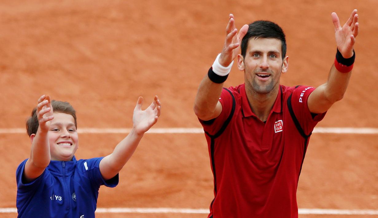 Petenis Serbia, Novak Djokovic, merayakan kemenangannya atas petenis Spanyol, Roberto Bautista Agut, bersama seorang ball boy dalam turamen tenis Prancis Terbuka 2016 di Roland Garros, Paris, (1/6/2016). (Reuters/Pascal Rossignol)