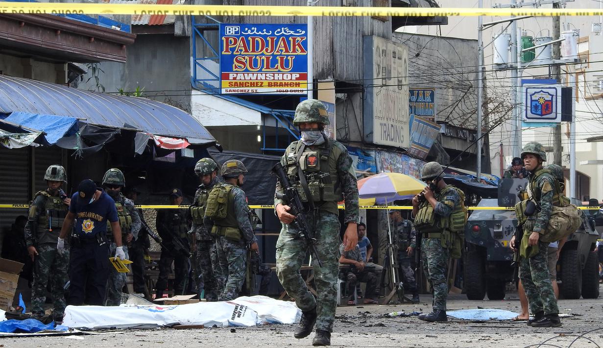 Polisi dan tentara berjaga pasca ledakan bom di Gereja Katolik Jolo, Filipina Selatan, Minggu (27/1). Bom kedua meledak di tempat parkir gereja ketika aparat setempat merespons. (Nickee Butlangan/AFP)