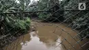 Kondisi jembatan gantung yang sudah tidak layak di kawasan Srengseng Sawah, Jakarta, Sabtu (12/6/2021). Kondisi jembatan gantung yang menjadi akses warga dari Cimanggis menuju Srengseng Sawah atau sebaliknya tersebut beralaskan bambu serta seng. (merdeka.com/Iqbal S. Nugroho)