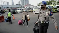 Polisi membantu membawakan barang penumpang yang terjaring razia travel gelap Ditlantas Polda Metro Jaya saat akan dipulangkan ke daerah asalnya, Jakarta, Kamis (29/4/2021). Sebanyak 115 kendaraan travel gelap diamankan. (Liputan6.com/Faizal Fanani)