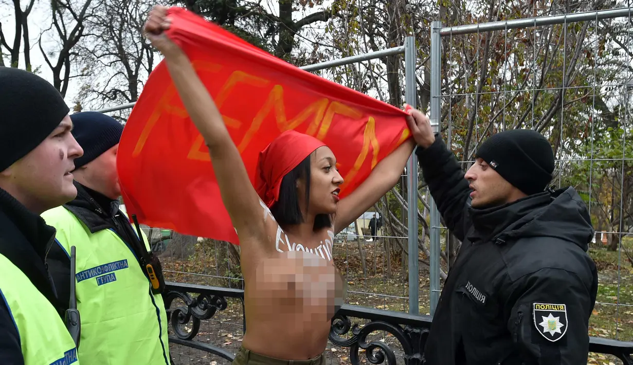 Petugas menghalau aktivis wanita gerakan hak perempuan Femen saat unjuk rasa memperingati 100 tahun Revolusi Bolshevik di pusat kota Kiev, Ukraina (7/11). (AFP Photo/Genya Savilov)
