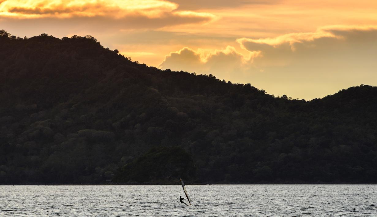 Seorang pria bermain selancar angin saat matahari terbenam di sebuah pantai di Banda Aceh (7/4). Kota Banda Aceh merupakan salah satu kota yang berada di Aceh dan menjadi ibukota Provinsi Aceh, Indonesia. (AFP Photo/Chaideer Mahyuddin)