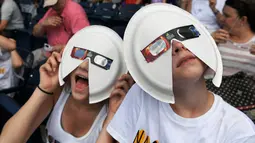 Dua anak laki-laki asal Dallas memakai kacamata khusus berhiaskan potongan piring plastik saat melihat gerhana matahari di Nashville, Tenn, Senin (21/8). Durasi terlama menikmati fenomena ini 2 menit 40 detik. (Shelley Mays/The Tennessean Via AP)