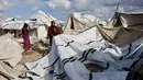 Para pengungsi di Gaza hanya punya dua pilihan tempat berlindung. Tampak dalam foto, seorang perempuan Palestina pengungsi merapikan terpal tenda keluarga saat wilayah tersebut dilanda hujan dan kondisi musim dingin yang dingin, di Kota Gaza pada 28 Desember 2025. (Omar AL-QATTAA/AFP)