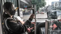 Penumpang memindai kartu sebelum menaiki bus listrik Transjakarta rute Kampung Melayu-Tanah Abang via Cikini (5M) saat uji coba di Terminal Kampung Melayu, Jakarta Timur, Selasa (26/7/2022). PT Transjakarta mengubah rute uji coba bus listrik yang sebelumnya jurusan Kampung Melayu-Tanah Abang (5F) agar masyarakat dapat menjajal secara merata sekaligus memperkenalkan jalur bus yang melayani mulai pukul 05.00-21.00 WIB. (merdeka.com/Iqbal S Nugroho)