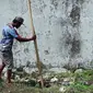 Seorang pria memasukkan kayu ke dalam lubang yang digunakan narapidana untuk kabur dari Lapas Kerobokan, Bali, Senin (19/6). Empat narapidana asing kabur melalui lubang sepanjang 15 m yang mengarah ke parit di luar bangunan Lapas. (AP /Firdia Lisnawati)