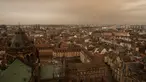 Pemandangan kota Strasbourg tampak diselimuti debu Sahara berwarna oranye bergerak di atas kota di Prancis timur (15/3/2022). Badai di gurun Sahara menciptakan badai besar hembusan angin, yang mengangkat pasir ke udara. (AP Photo/Jean-Francois Badias)