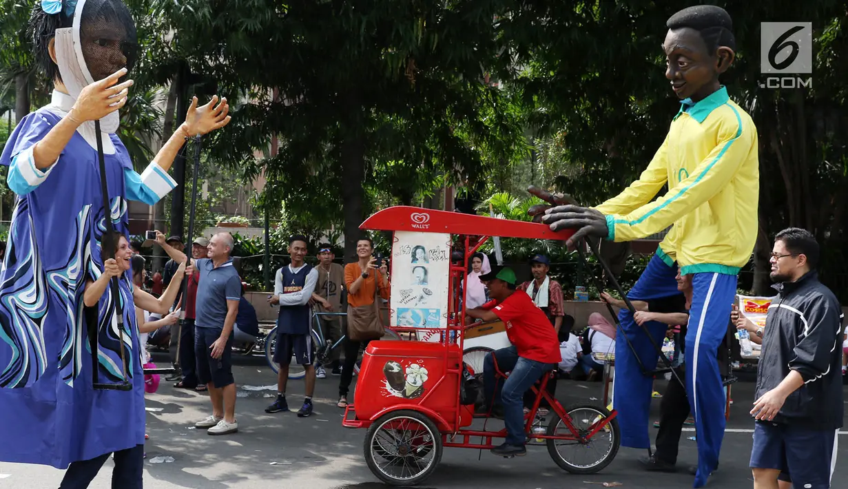 Dua boneka asal Prancis dari Kelompok teater Les Grandes Personnes hibur warga saat CFD di Jakarta, Minggu (9/7). Kedubes Prancis dan Institute Francais Indonesia menggelar acara penggalangan dana Diplomasi Solidaritas. (Liputan6.com/Immanuel Antonius)