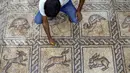 Seorang pria menggunakan kuas untuk membersihkan mosaik era Bizantium yang ditemukan di Bureij, Jalur Gaza, Palestina, 18 September 2022. Seorang petani Palestina menemukan mosaik lantai Bizantium berornamen ketika mencoba menanam pohon zaitun di tanahnya di Jalur Gaza. (MOHAMMED ABED/AFP)