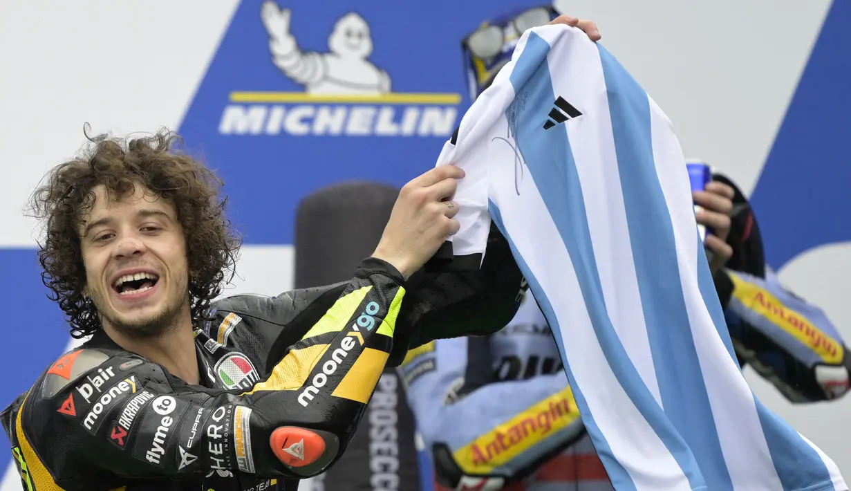 <p>Pebalap Tim Mooney VR46, Marco Bezzecchi merayakan kemenangan dengan jersey Timnas Argentina bertandatangan Lionel Messi saat menjuarai MotoGP Argentina 2023 di Aut&oacute;dromo Termas de R&iacute;o Hondo, Argentina, Senin (03/04/2023) dini hari WIB. Selebrasi tersebut diketahui meniru sang gurunya, Valentino Rossi yang dilakukan pada musim 2015 silam. (AFP/Juan Mabromata)</p>