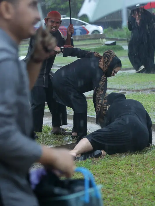 Derasnya hujan, dan banyaknya genangan air di area pemakaman Sutan Bhatoegana membuat beberapa tempat licin. Terlihat salah seorang pelayat terjatuh.  (Bambang E. Ros/Bintang.com)