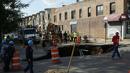 Sejumlah petugas bekerja di dekat lubang besar (sinkhole) di wilayah Brooklyn, New York, Selasa (4/8/2015). Lubang yang terbentuk di persimpangan pemukiman Sunset Park itu disebabkan erosi dan merusak pipa air serta aspal jalan. (AFP/Kena Betancur)