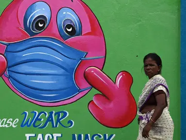 Seorang wanita berjalan melewati mural kesadaran virus corona COVID-19 di sepanjang pinggir jalan di Chennai, India, 13 September 2021. India bersiap hadapi kemungkinan lonjakan kasus COVID-19 sekitar musim festival September hingga November. (ARUN SANKAR/AFP)