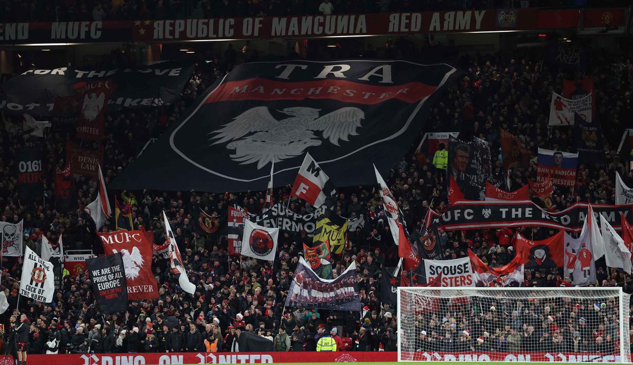 Dengan tambahan tiga poin, Setan Merah kini mengoleksi 29 poin dan naik ke peringkat ke-5. Tampak dalam foto, para penggemar mengibarkan bendera menjelang dimulainya pertandingan sepak bola Liga Premier Inggris antara Manchester United dan Newcastle United di Stadion Old Trafford, pada 26 Desember 2025 waktu setempat atau Sabtu (27/12/2025) dini hari WIB. (Darren Staples/AFP)
