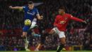 Bek Everton, Seamus Coleman, berebut bola dengan striker Manchester United, Marcus Rashford, pada laga Premier League di Stadion Old Trafford, Manchester, Minggu (15/12). Kedua klub bermain imbang 1-1. (AFP/Oli Scarff)