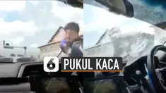 Pria yang mengenakan helm dan jaket itu terlihat marah-marah dan mendobrak kaca pintu depan mobil.