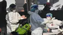 Petugas medis (kiri) mengambil sampel usap hidung dari seorang polisi di pusat pengujian virus corona COVID-19, Seoul, Korea Selatan, Rabu (16/2/2022). Kasus COVID-19 harian Korea Selatan meningkat tajam mencapai angka tertinggi baru yaitu lebih dari 90 ribu. (Jung Yeon-je/AFP)