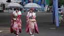 Dua wanita Jepang berjalan di bawah naungan payung dan balutan kimono usai menghadiri Coming of Age Day atau Hari Kedewasaan di Taman Toshimaen, Tokyo, Jepang, Senin, (8/1). (AP Photo/Shizuo Kambayashi)