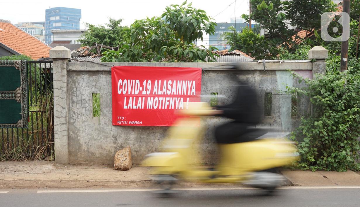 Pengendara motor melintas di depan poster protes warga terhadap pembangunan flyover di kawasan Tanjung Barat, Jakarta, Rabu (15/7/2020). Dalam poster protes tersebut, warga menuntut agar pembayaran pelunasan pembebasan lahan segera diselesaikan secara serentak. (Liputan6.com/Immanuel Antonius)