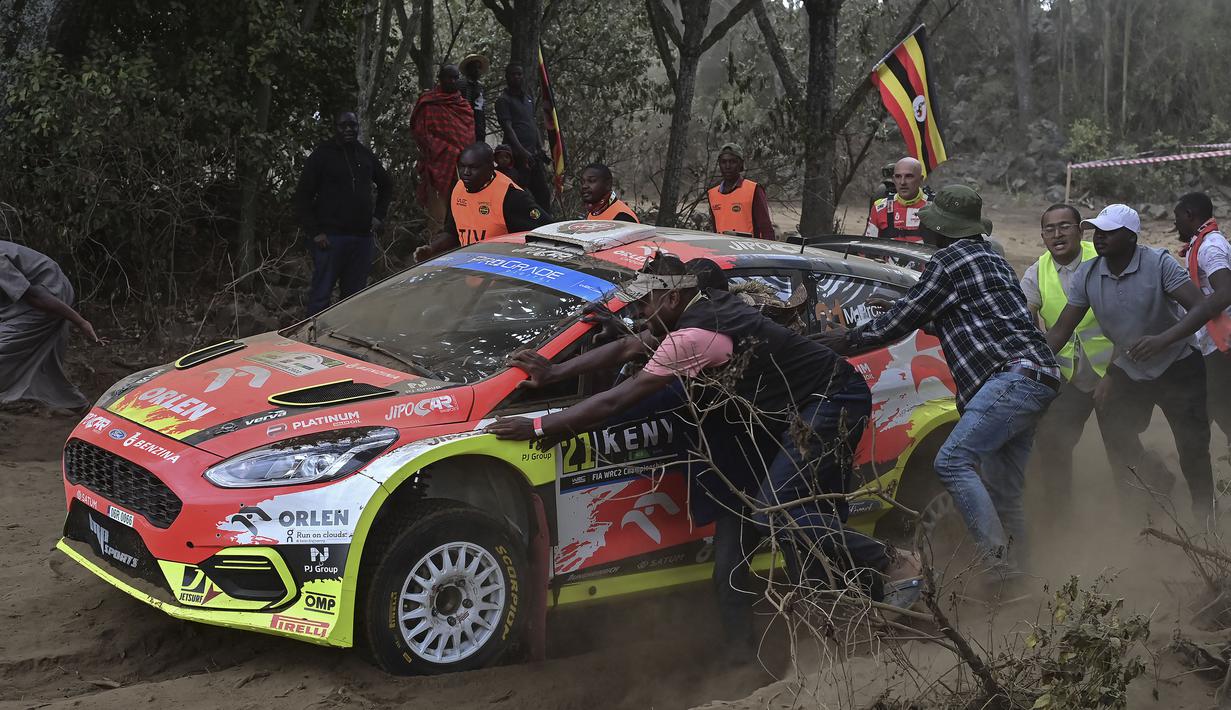 Sejumlah penonton membantu mendorong mobil Ford Fiesta MkII milik tim reli Republik Ceska yang dikendarai oleh Martin Prokop dan Zdenek Jurka karena mogok dalam ajang Safari Rally Kenya 2022 yang berlangsung di kota tepi danau Naivasha pada 24 Juni 2022. (AFP/Tony Karumba)