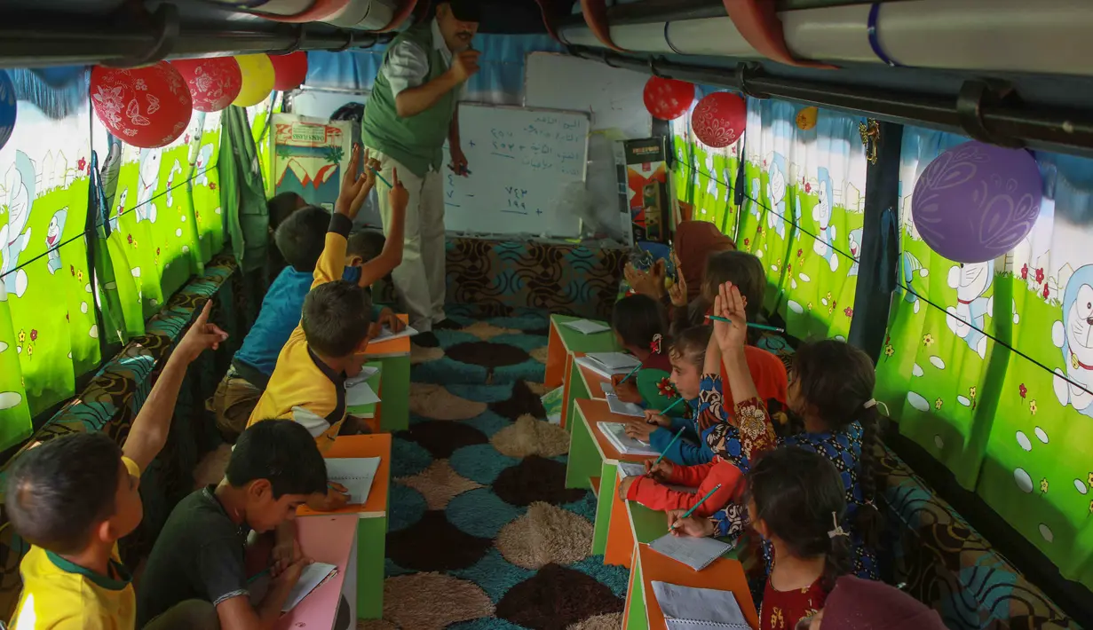Anak-anak Suriah mengikuti pelajaran di dalam bus yang dikonversi menjadi ruang kelas di desa Hazano di barat laut Suriah (15/9/2019). Pelajaran di kelas bus ini yaitu bahasa Arab, matematika, sains, dan kadang-kadang bahasa Inggris , serta menyanyi dan menggambar. (AFP Photo/Aaref Watad)