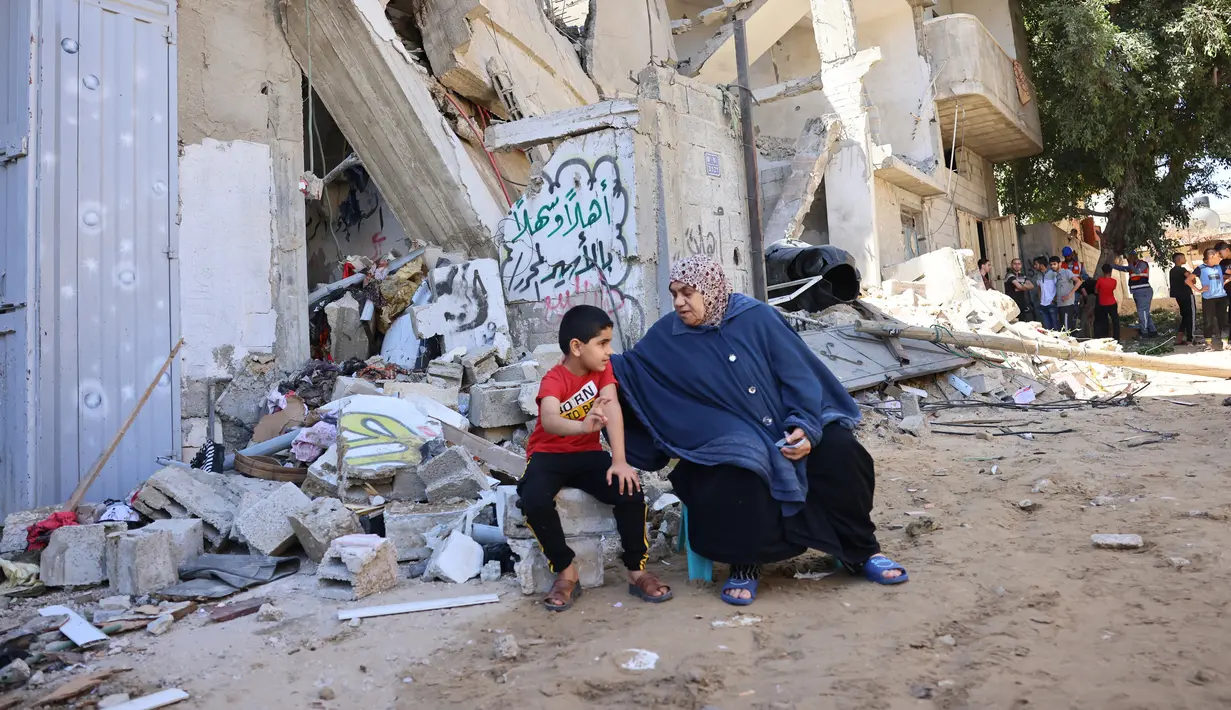 Warga Palestina duduk di tengah puing-puing setelah serangan udara Israel di Rafah, Jalur Gaza, Palestina, 19 Mei 2021. Serangan udara Israel terus mengguncang Gaza di tengah dorongan diplomatik internasional untuk menengahi gencatan senjata. (SAID KHATIB/AFP)