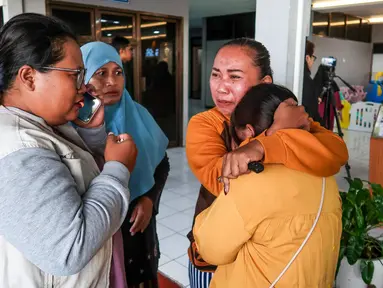 Anggota keluarga dan kerabat menunggu kabar terbaru tentang operasi pencarian sebuah kapal feri yang tenggelam di lepas pantai Bali, di Pelabuhan Ketapang, Banyuwangi, Jawa Timur, pada Kamis 3 Juli 2025. (Foto oleh AFP)