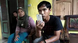 Saudara Sumarti Ningsih, Suyitno (kanan) berbincang lewat ponsel di desa mereka di Cilacap, Jawa Tengah , Indonesia (8/11).Selain Sumarti Ningsih, Seneng Mujiasih juga menjadi korban pembunuhan pada November 2014. (REUTERS/Idhad Zakaria)