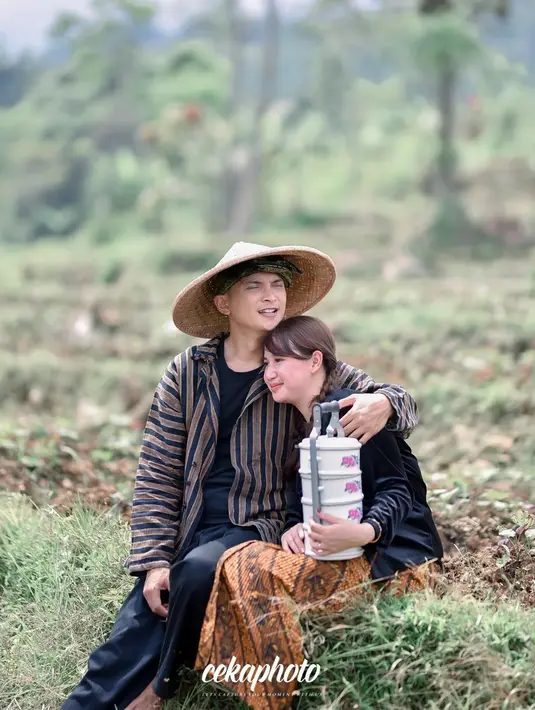 Salah satu pose paling manis adalah saat keduanya duduk di pematang sawah. Sang calon istri tampak menyandarkan kepala di bahu Reiner. Uniknya, mereka juga membawa rantang sebagai properti pemotretan. Rantang memang identik dibawa istri ke sawah untuk kirim makanan pada suami. (Liputan6.com/IG/@cekaphoto)