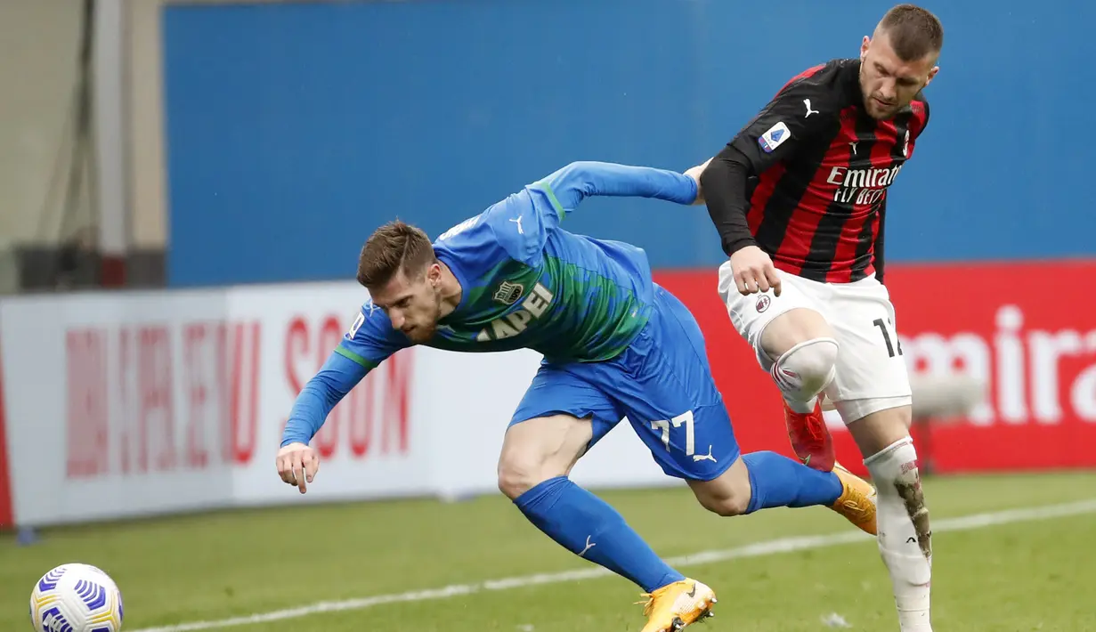 Pemain Sassuolo Giorgos Kyriakopoulos (kiri) memperebutkan bola dengan pemain AC Milan Ante Rebic pada pertandingan Serie A di Stadion San Siro, Milan, Italia, Rabu (21/4/2021). AC Milan kalah 1-2 dari Sassuolo. (AP Photo/Antonio Calanni)