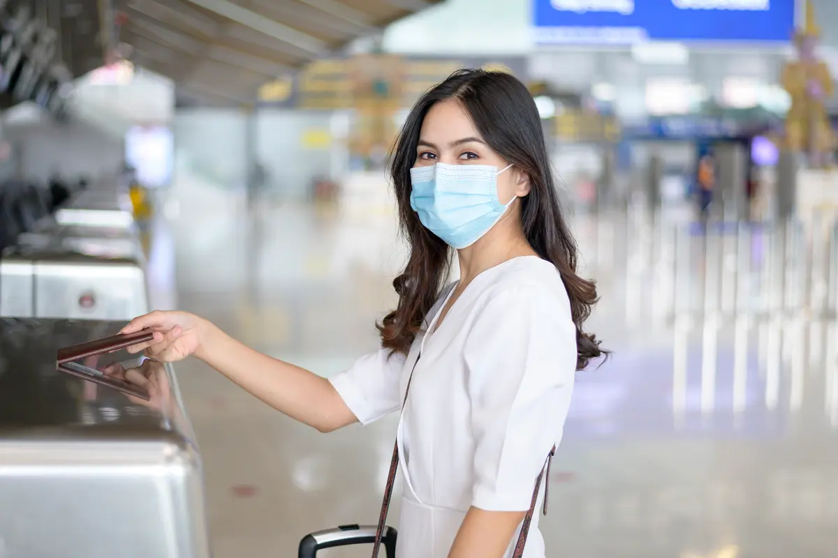 perempuan di bandara traveling pakai masker