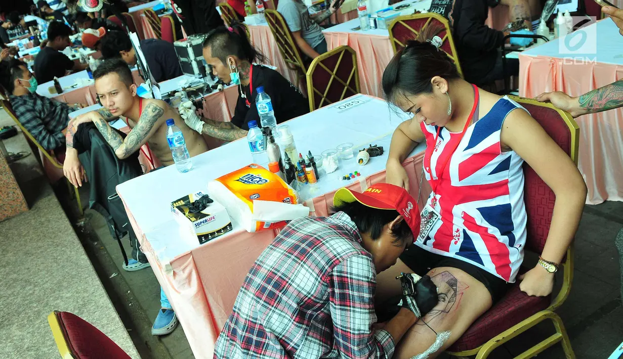 Seorang wanita saat ditato dibagian pahanya saat mengikuti Event tato di salah satu Mal di Jakarta, Sabtu (23/9). Selain Lomba Tatto dalam acara tersebut ada juga pelatihan cara mentato yang benar dan rapih. (Liputan6.com/Helmi Afandi)