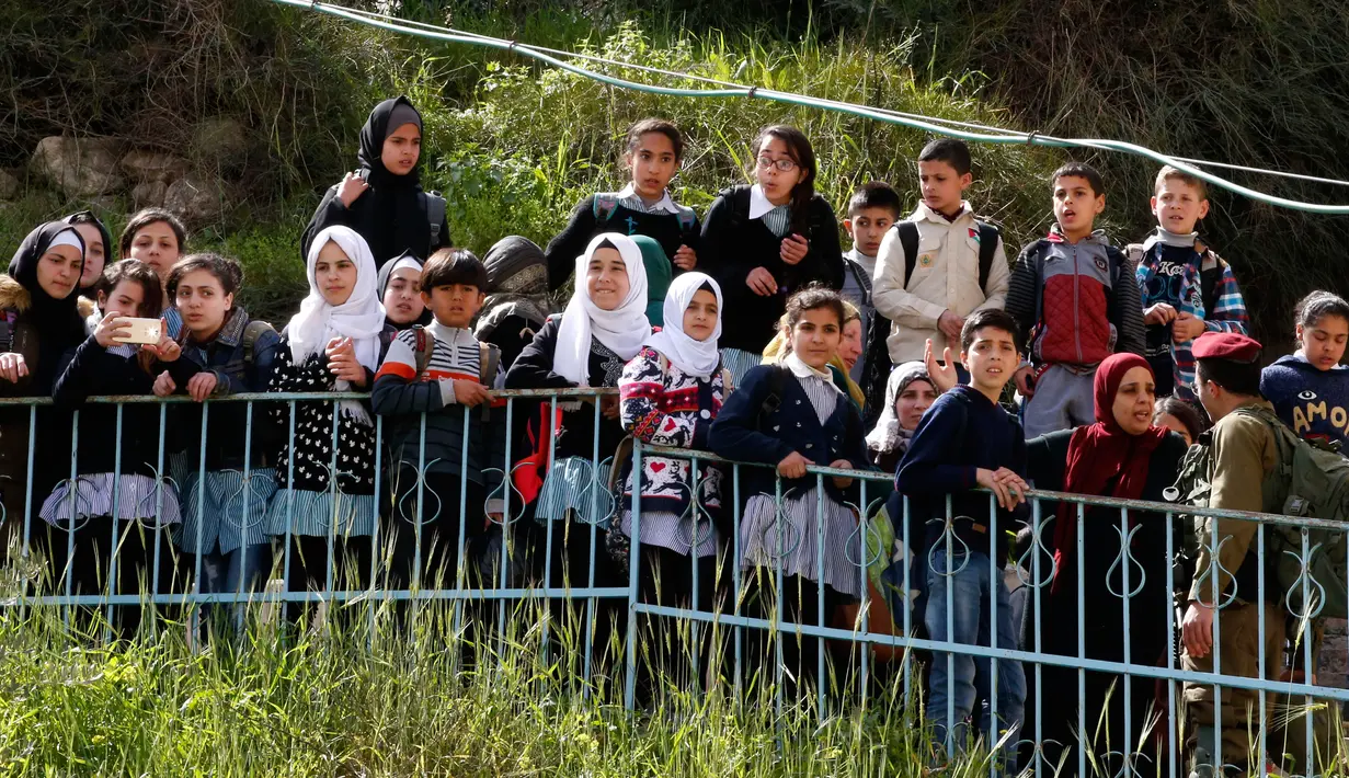 Ekspresi anak-anak Palestina saat menyaksikan warga Yahudi merayakan Hari Purim di Jalan al-Shuhada, Kota Hebron, Tepi Barat, Kamis (1/3). Hari Purim dirayakan dengan parade dan pesta kostum. (AFP PHOTO/HAZEM BADER)