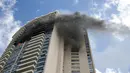 Kepulan asap hitam menyelimuti bagian gedung saat terjadi kebakaran di apartemen Marco Polo, Honolulu (14/7). Menurut petugas setempat, titik api pertama kali muncul di lantai 26 hingga akhirnya menjalar ke beberapa bagian gedung. (AP Photo/Marco Garcia)