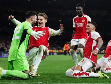 Pemain Arsenal merayakan kemenangan setelah David Raya berhasil menepis dua tendangan penalti dari pemain Porto pada laga leg kedua 16 besar Liga Champions 2023/2024 di Emirates Stadium, London, Inggris, Rabu (13/03/2024). (AFP/Adrian Dennis)