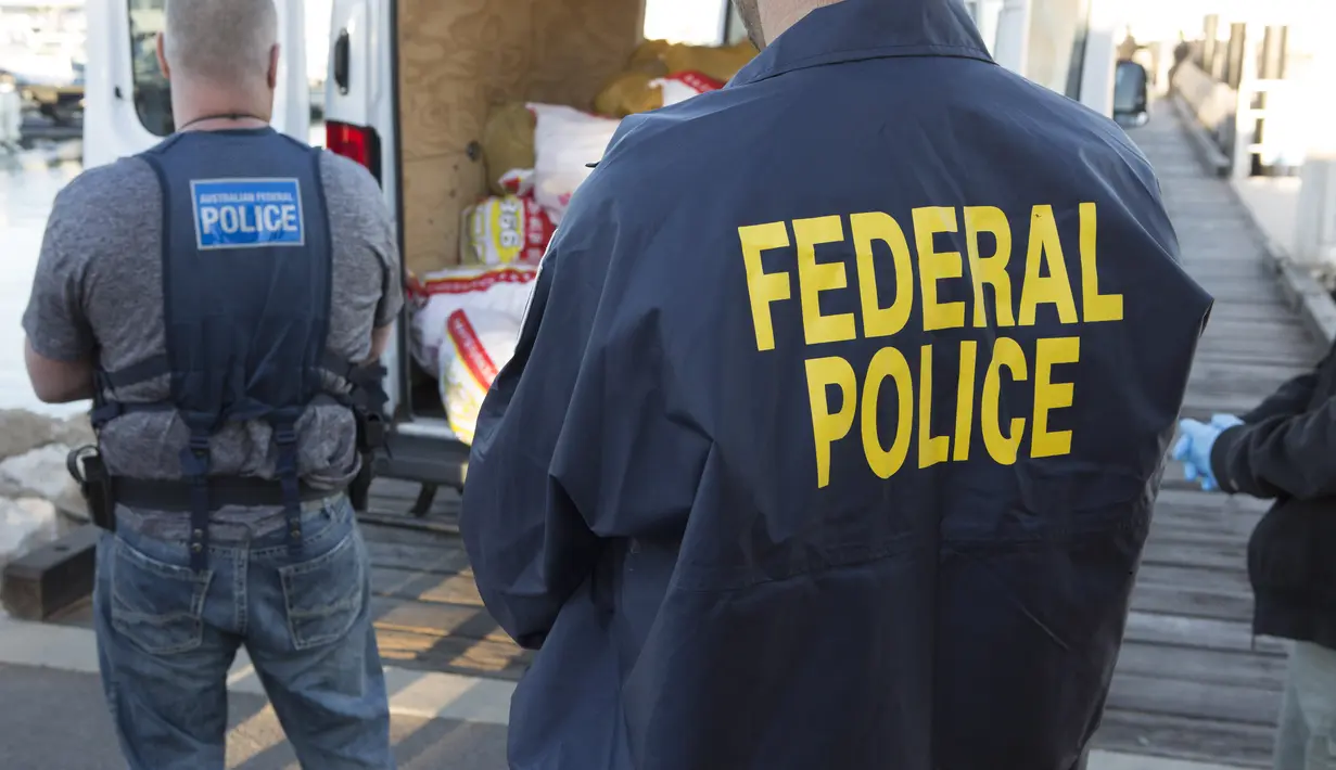 Polisi Federal Australia berjaga di dekat mobil van yang berisi karungan narkoba di Geralton, Australia (21/12). Polisi memperkirakan narkoba sebanyak 1,2 ton tersebut memiliki nilai 1,04 miliar dolar Australia. (AFP Photo/Australia Federal Police)